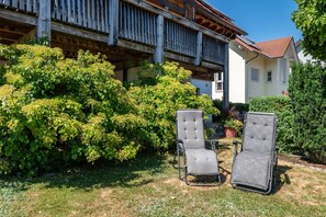 Ein Garten mit zwei Stühlen und einem Gebäude mit Balkon.