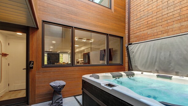 A hot tub in a covered outdoor area with wooden walls and large windows. - Managed by Park City Lodging-Easy Walk to Ski Lifts - Private Hot Tub - Views! (Park City)