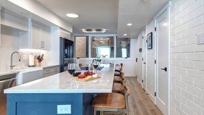 A modern kitchen with a large island, bar stools, and a view into the dining area. - Managed by Park City Lodging-Easy Walk to Ski Lifts - Private Hot Tub - Views! (Park City)