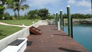 Una banchina in legno che si protende sull'acqua calma, con una barriera in cemento su un lato e lampioni verdi dall'altro.
