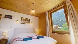Ein Zimmer mit Holzwänden, einem Bett, einem Fenster mit Vorhängen und Wandleuchten.