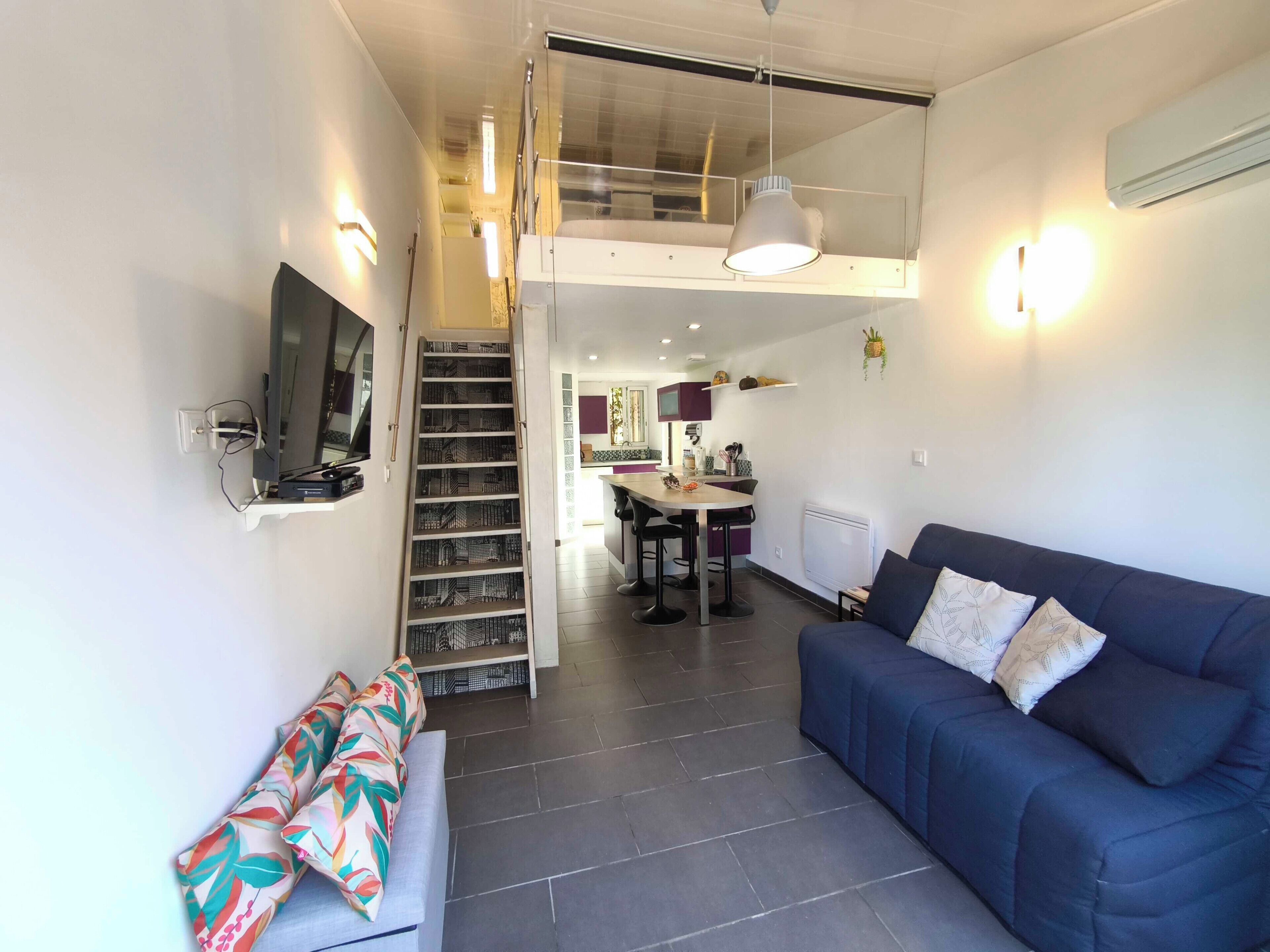 Ein modernes Apartment mit Wohnzimmer, Essbereich und Küche. Eine Treppe verbindet die beiden Etagen.