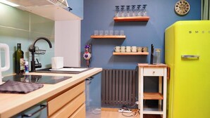 Een compacte keuken met een modern ontwerp, met een felgroene koelkast, houten kastjes en een inbouwfornuis.