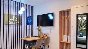Een moderne kantoorruimte met een houten bureau, stoelen, een televisie en een decoratief wandpaneel.
