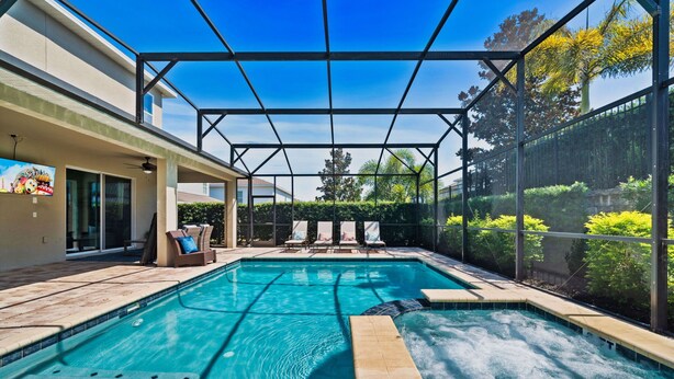 A swimming pool with a glass enclosure, lounge chairs, and a patio area. - Magical Memories Villa 10bd Near Disney (Kissimmee)