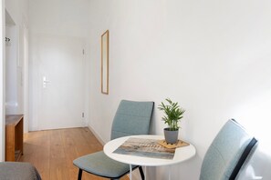 Ein Zimmer mit einer weißen Tür, einem runden Tisch mit einer Pflanze und zwei Stühlen.
