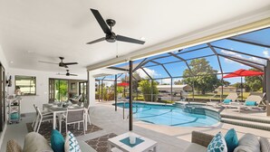 A spacious indoor pool area with a glass ceiling, outdoor seating, and a dining area. - Seaside Villa Southern Belle - 3/2 Southeast paradise with spa and outside TV (Cape Coral)