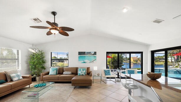 A spacious living area with a large window, a ceiling fan, and a pool view. - Seaside Villa Southern Belle - 3/2 Southeast paradise with spa and outside TV (Cape Coral)