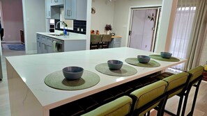 Una cocina moderna con una isla central, un comedor con sillas y vistas al espacio de estar contiguo.