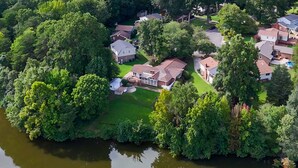 Vue aérienne d’un quartier résidentiel avec des maisons, un lac et la végétation environnante.