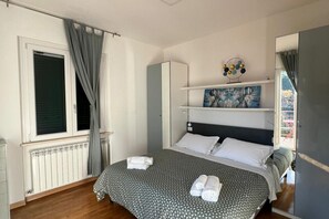 Un dormitorio con cama, radiador, armario y un cuadro en la pared.