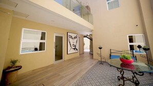 A multi-level residential interior with a staircase, a glass table with plants, and artwork on the walls. - PrivateStudio/DoubleBed+CouchBed/Near Border (Tijuana)