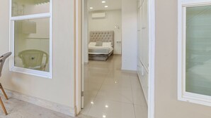 A hotel room with a large bed, a chair, and a view of the hallway. - PrivateStudio/DoubleBed+CouchBed/Near Border (Tijuana)
