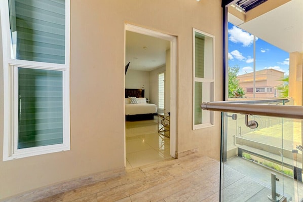 A corridor with a bed in the background, a glass door, and a balcony with a railing. - ComfyStudio w/QueenBed/Tijuana Near USBorder (Tijuana)