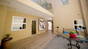 Un intérieur à plusieurs niveaux, doté d’une balustrade en verre, d’un espace repas avec une table en verre et d’un escalier menant à l’étage supérieur.