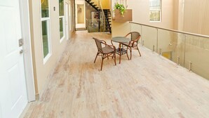 Un couloir doté d’un plancher en bois, d’une rambarde en verre et d’une table avec des chaises.