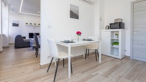 Una cuina moderna amb armaris blancs, una taula de dinar amb cadires, un microones i un petit moble decoratiu.