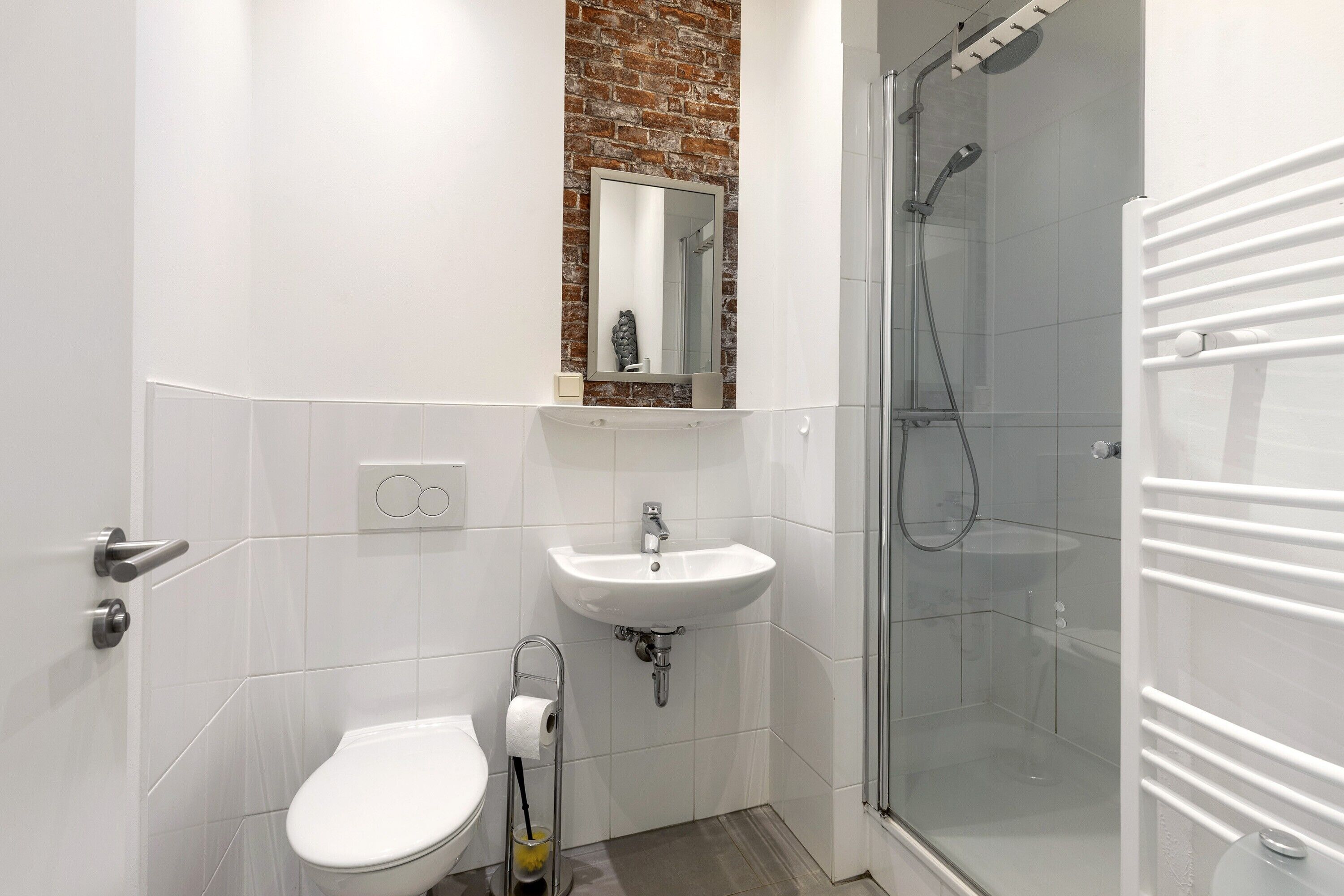 Ein Badezimmer mit Toilette, Waschbecken, Spiegel und einer Duschkabine.