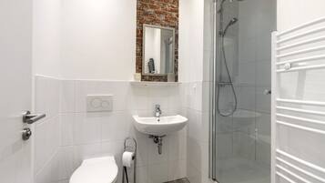 Ein Badezimmer mit Toilette, Waschbecken, Spiegel und einer Duschkabine.