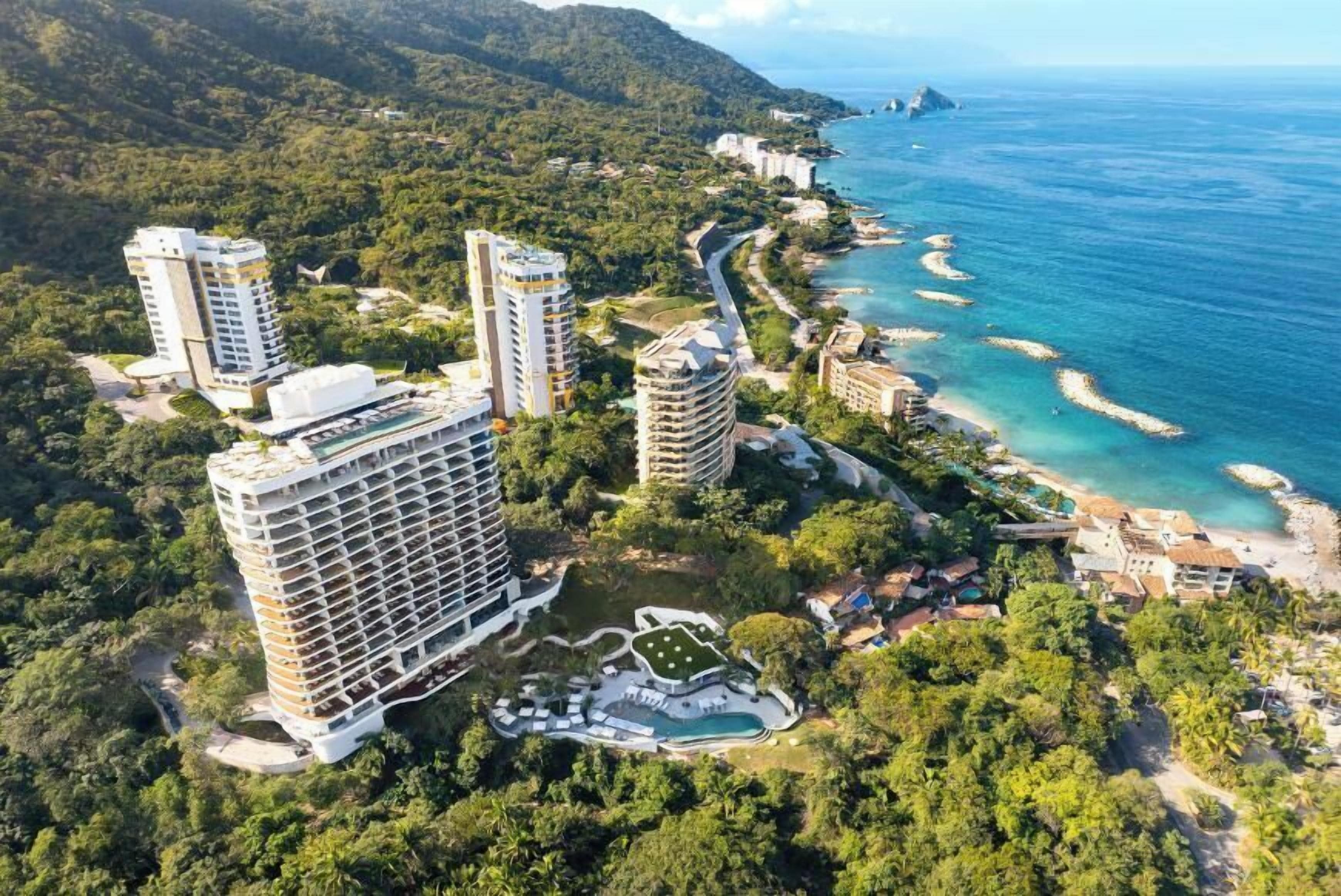 A coastal hotel with multiple high-rise buildings, a beachfront, and a landscaped pool area.