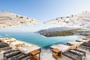 A rooftop infinity pool with lounge chairs and umbrellas overlooking a coastal view. - Garza Blanca Sanctuary (Puerto Vallarta)
