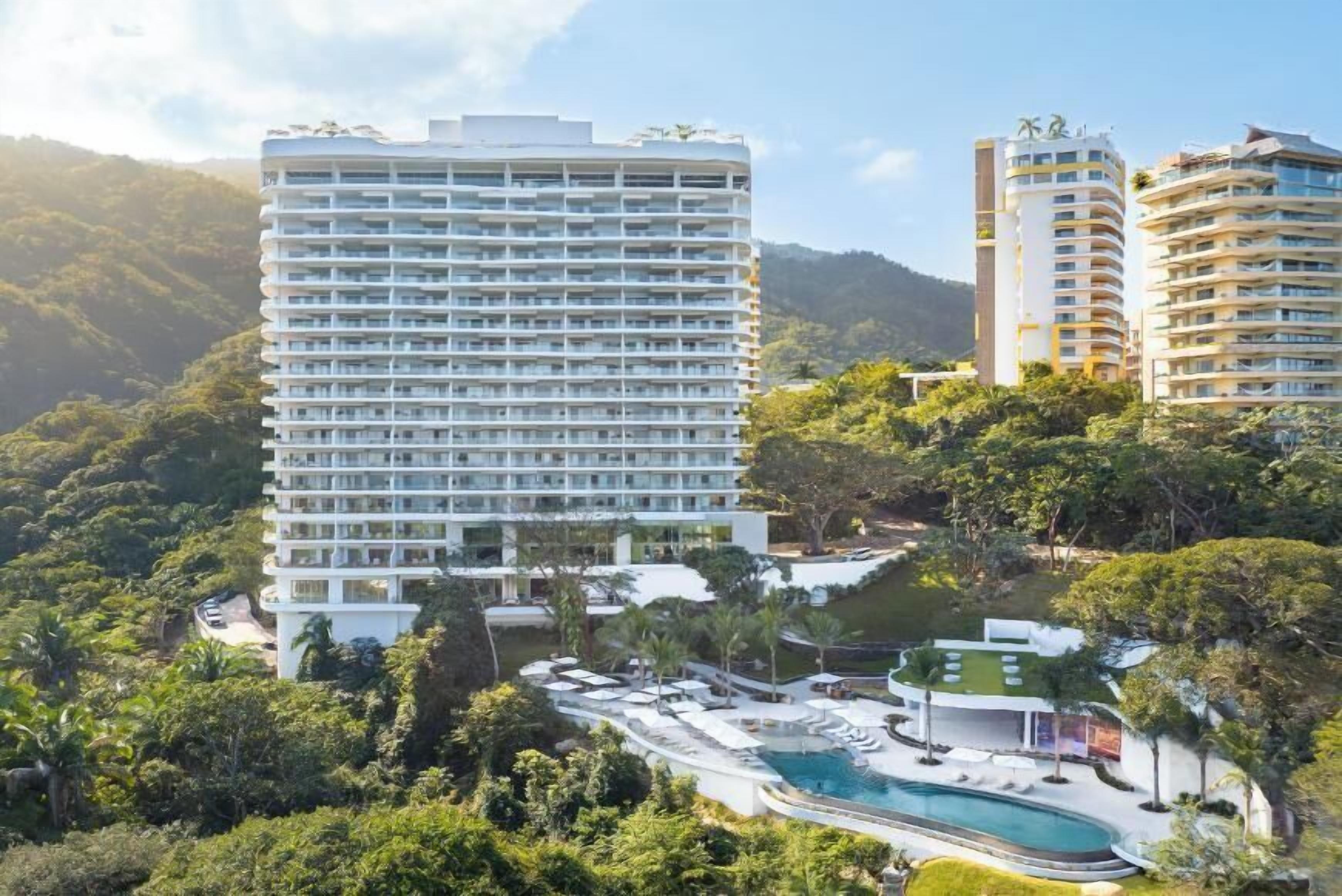 A high-rise hotel with multiple balconies, a swimming pool, and lush greenery surrounding the property.