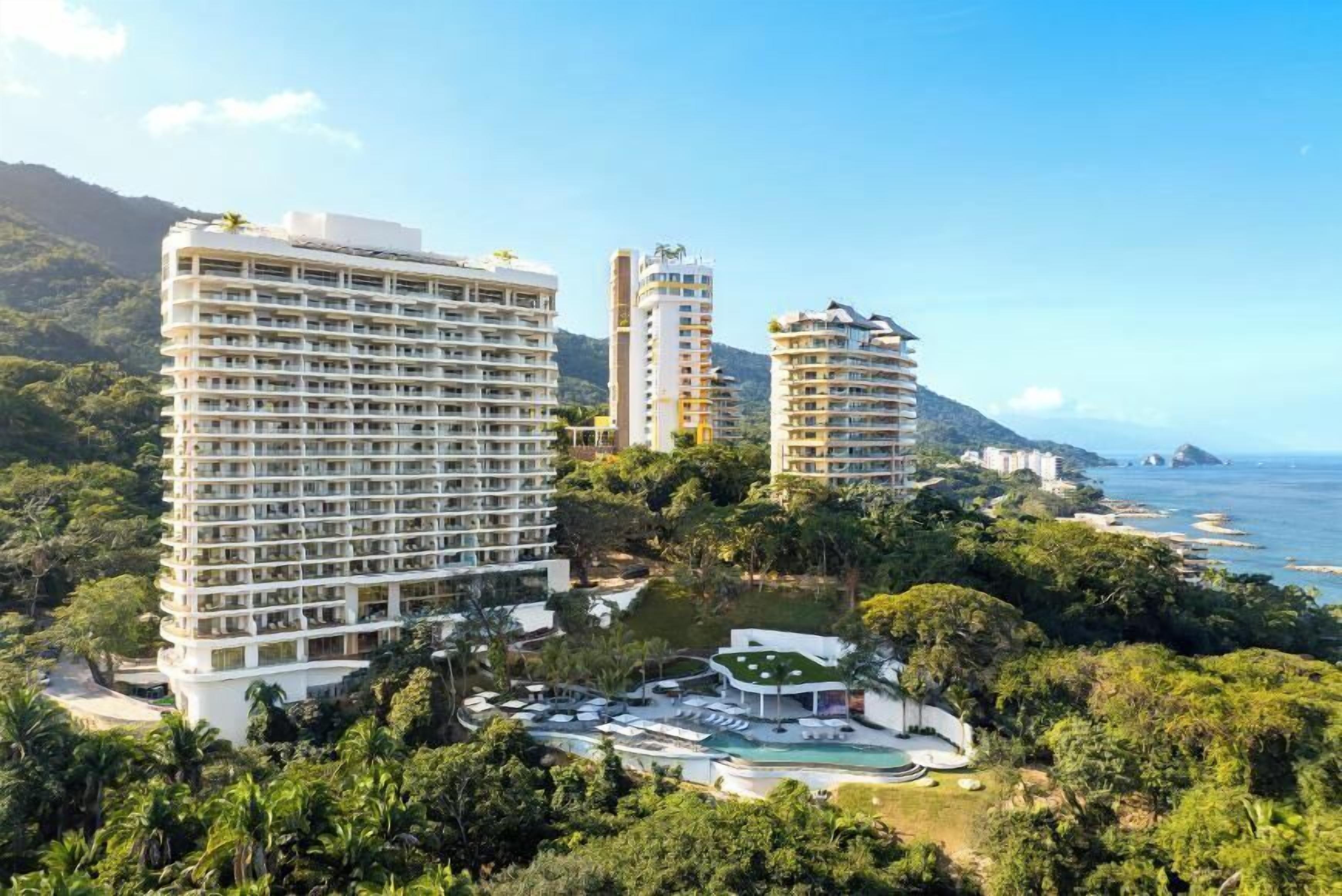 A high-rise hotel with multiple floors, a pool area, and a view of the ocean.