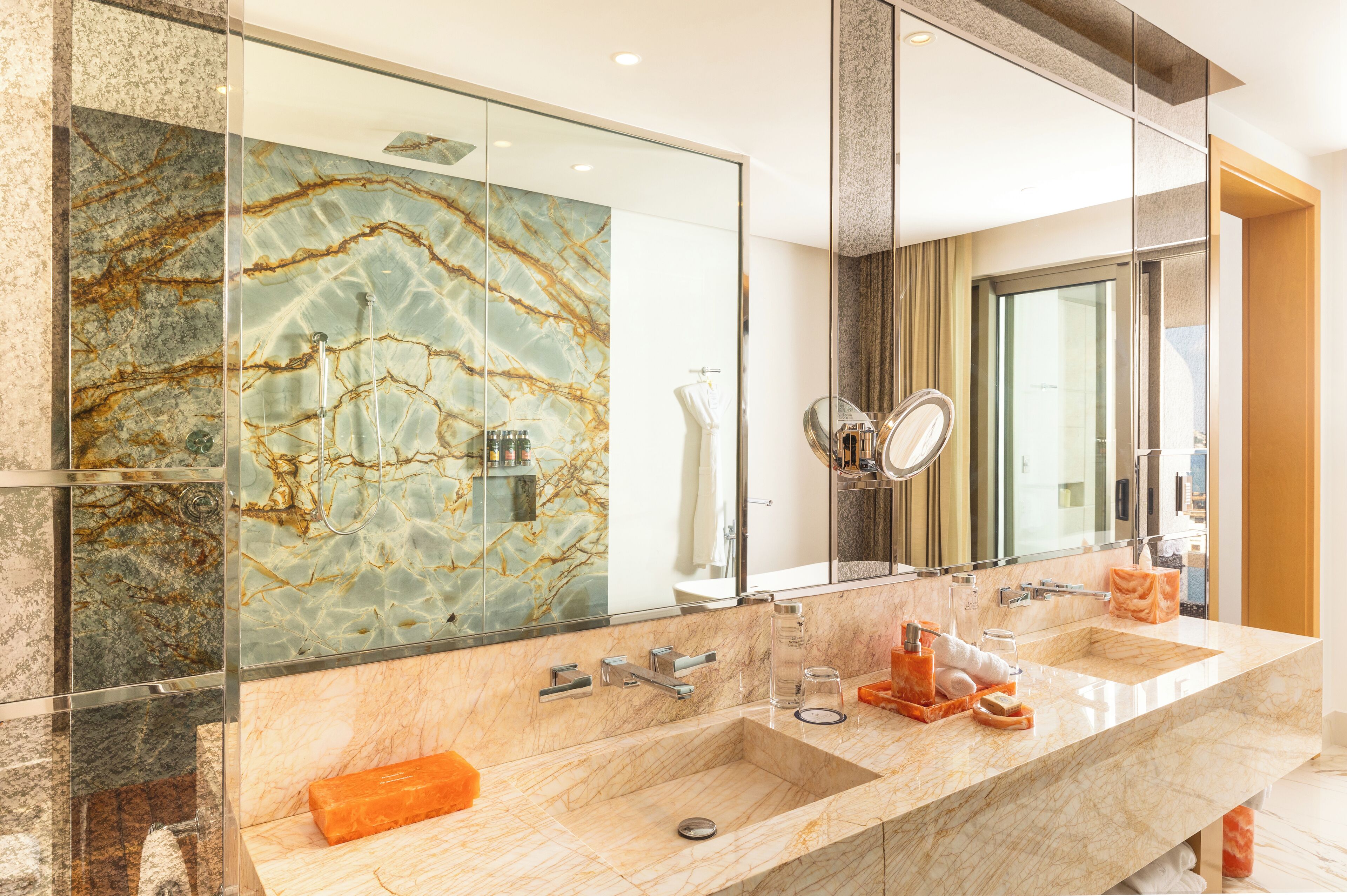 A modern bathroom with a large mirror, two sinks, and a marble backsplash.
