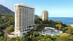 Un hotel de gran altura con varios balcones, una zona de piscina y vista al océano.