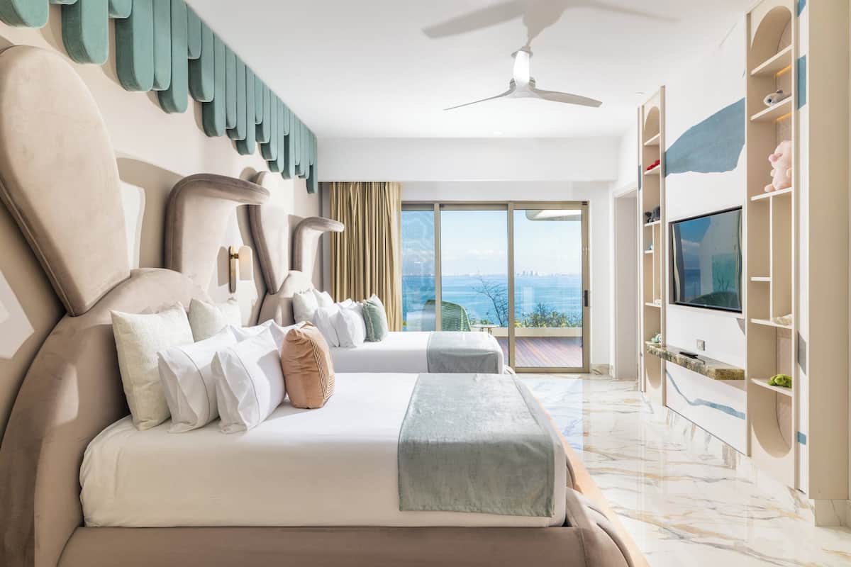 A modern hotel room with a large bed, a TV, and a balcony with a city view.