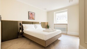 Una habitación de hotel moderna con una cama grande, una mesita de noche, un ventanal con vistas y un radiador.