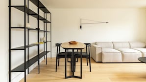 En moderne stue med sofa, rundt bord og sorte metalreoler.