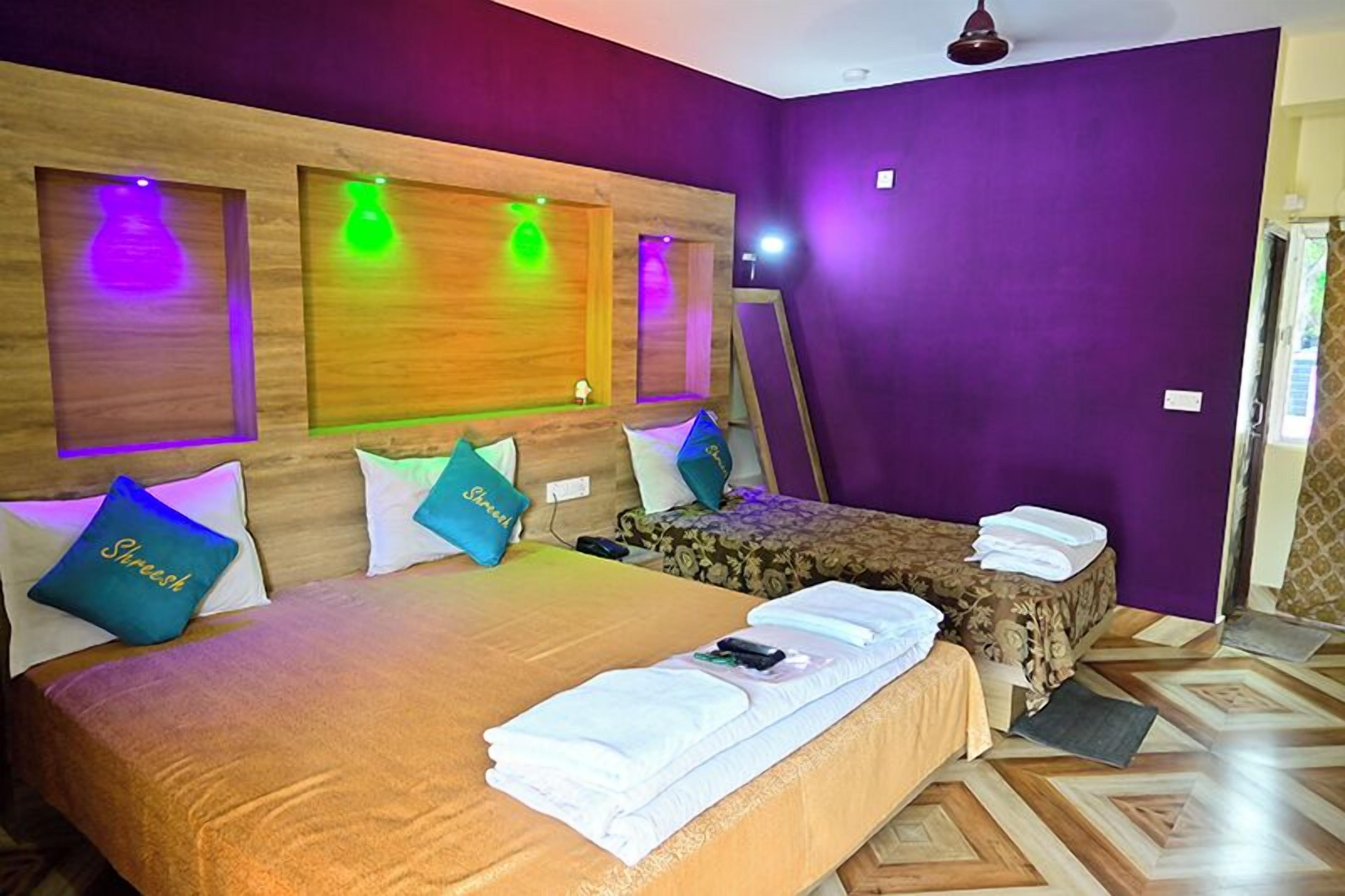 Quarto de hotel com uma cama grande, uma cama menor e um espelho. Há almofadas nas camas e uma toalha no chão.