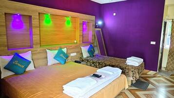 Quarto de hotel com uma cama grande, uma cama menor e um espelho. Há almofadas nas camas e uma toalha no chão.
