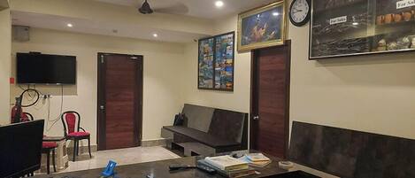 A room with a desk, computer, chair, sofa, and artwork on the walls.