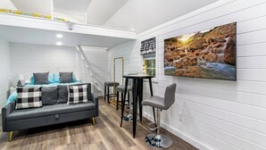 Una habitación moderna con una cama, un sofá, una mesa de comedor y un televisor en la pared.