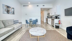 Een moderne woonkamer met een bank, een ronde salontafel en een eethoek met stoelen.