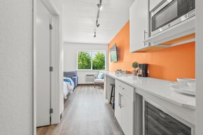 A modern kitchen with white cabinets, a microwave, and a large window. - Chic 1-bedroom Micro Studio Apartment (Cedar Falls)