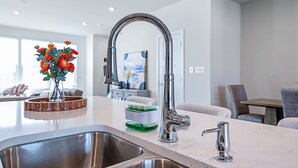 Una cocina moderna con un lavamanos de acero inoxidable, un grifo de cuello alto y un cuenco de madera como elemento decorativo.