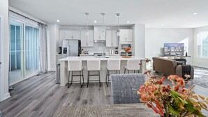 Una cocina moderna con una isla central, taburetes de bar e iluminación colgante.
