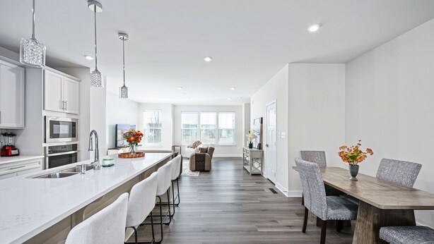 Una cocina moderna con armarios blancos, una isla central con taburetes y luminarias colgantes.