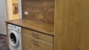 A compact kitchen with a built-in washing machine, wooden cabinets, and a tiled floor. - Spacious 160 sqm apartment in central Göppingen for families, fitters, groups (Göppingen)