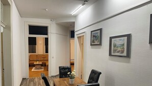 A dining area with a wooden table and black chairs, a radiator on the wall, and a door leading to another room. - Spacious 160 sqm apartment in central Göppingen for families, fitters, groups (Göppingen)