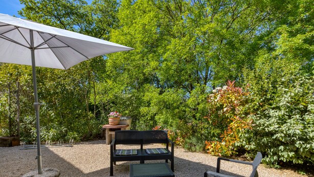 Ein Sitzbereich im Freien mit Tisch, Stühlen und Sonnenschirm.