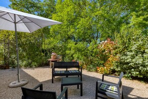 An outdoor seating area with a table, chairs, and an umbrella. - Gîte La Colline des Pins with Private Garden, Wi-Fi, and Air Conditioning (Aniane)