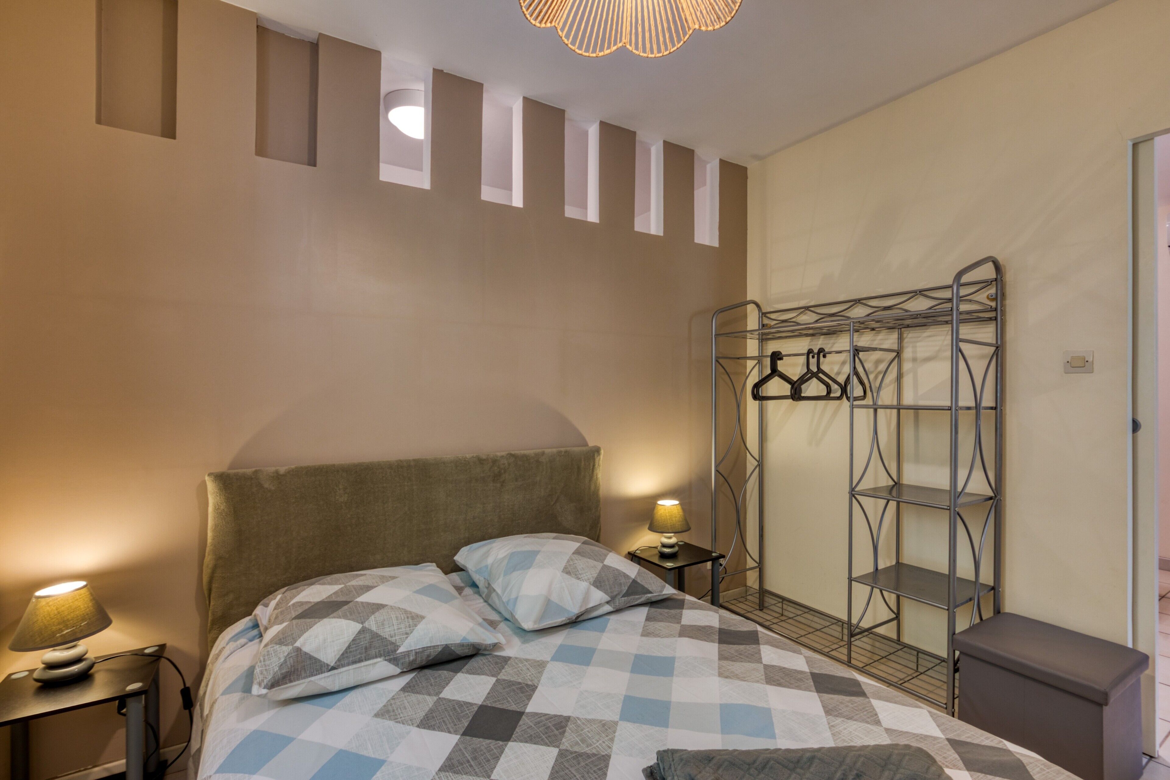 Una camera da letto con un letto, una lampada da comodino e un armadio metallico con spazio per appendere.