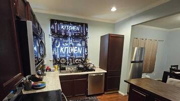 A modern kitchen with dark wood cabinets, a stainless steel refrigerator, and a granite countertop.