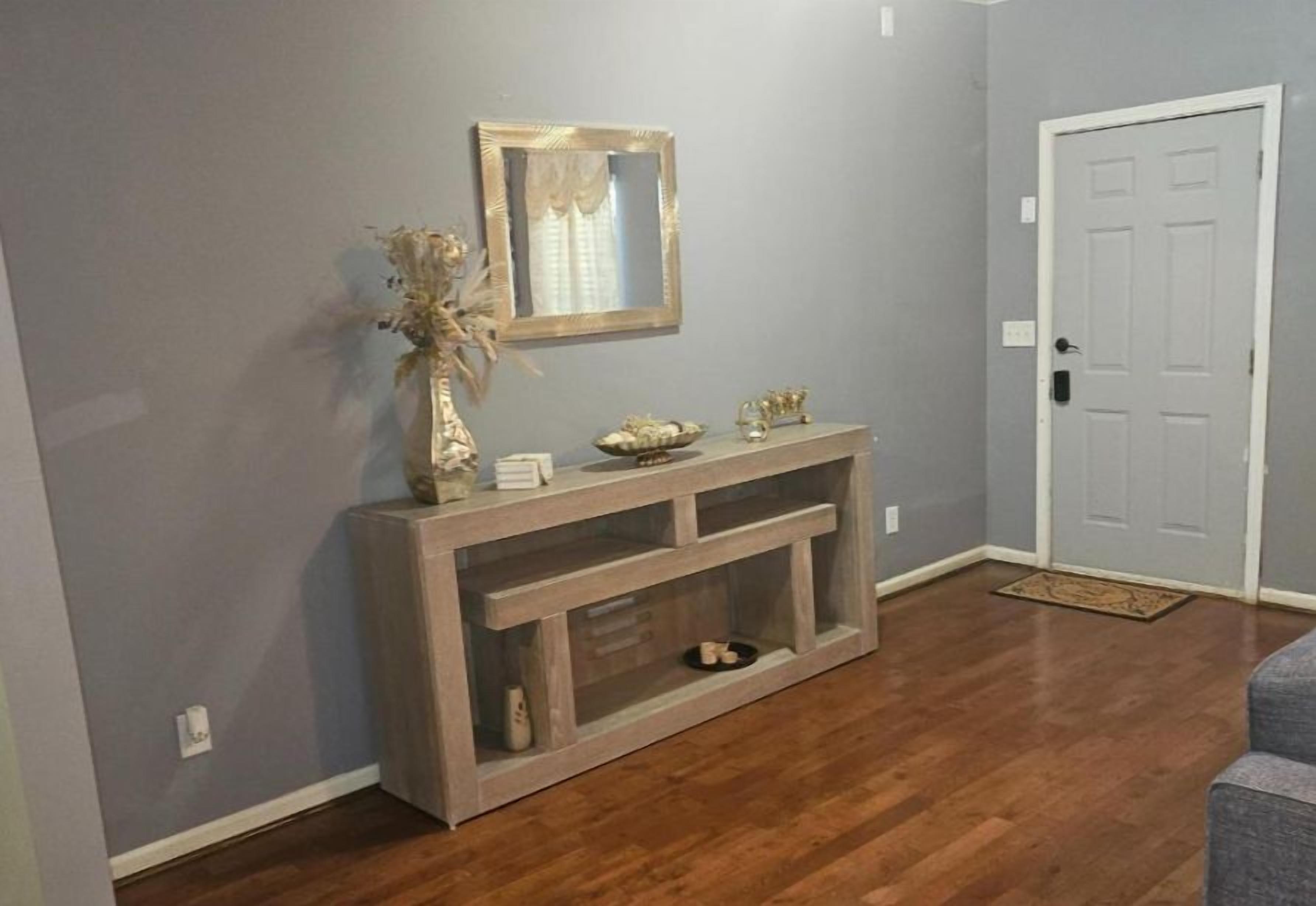 A hallway with a wooden console table, a mirror, and a door.