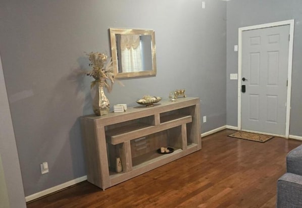 A hallway with a wooden console table, a mirror, and a door.