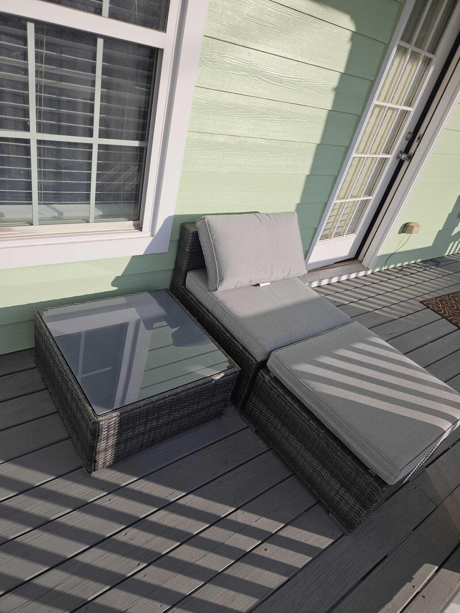 A covered outdoor seating area with a cushioned bench and a glass-top table.